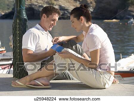 A couple sitting by a harbour writing postcards View Large Photo Image Picture - A couple sitting by a harbour writing postcards. Fotosearch
