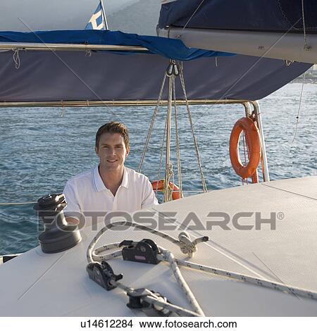 Picture - A man holding the wheel of a sailing boat. Fotosearch