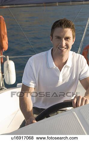 A man holding the wheel of a sailing boat View Large Photo Image Stock Photo - A man holding the wheel of a sailing boat. Fotosearch