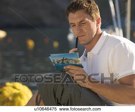 Stock Photography - A man writing a postcard. Fotosearch