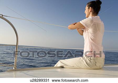 Stock Image - A woman relaxing on a boat. Fotosearch