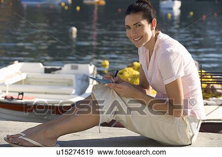 A woman sitting by a harbour writing a postcard View Large Photo Image Stock Photo - A woman sitting by a harbour writing a postcard. Fotosearch
