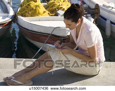 A woman sitting by a harbour writing a postcard View Large Photo Image Stock Photograph - A woman sitting by a harbour writing a postcard. Fotosearch