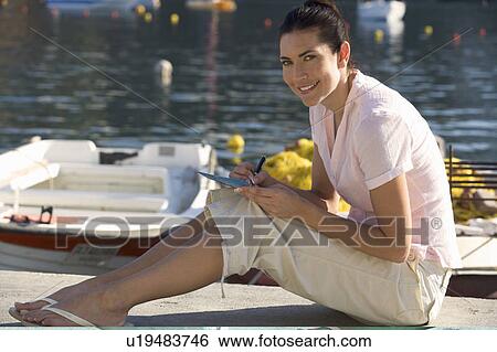 A woman sitting by a harbour writing a postcard View Large Photo Image Stock Photograph - A woman sitting by a harbour writing a postcard. Fotosearch