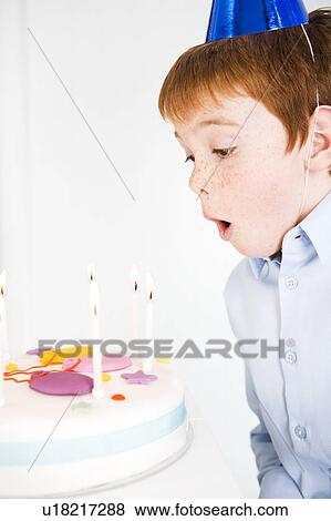 Stock Photo - boy blowing out candles on birthday cake. Fotosearch