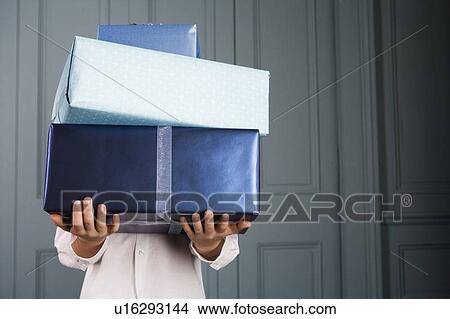 Picture - boy carrying pile of presents face obscured. Fotosearch