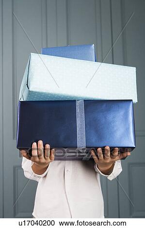 Stock Image - boy carrying pile of presents face obscured. Fotosearch