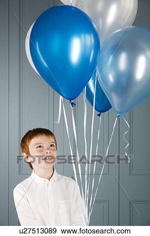boy looking up at balloons he's holding View Large Photo Image Stock Photo - boy looking up at balloons he's holding. Fotosearch