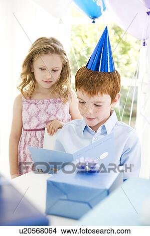 Picture - boy reading birthday card at his party. Fotosearch