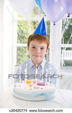 boy sitting at table with birthday cake View Large Photo Image Picture - boy sitting at table with birthday cake. Fotosearch