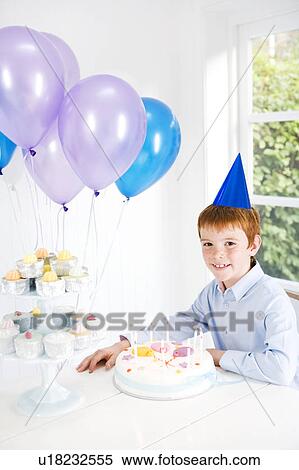 Boy sitting at table with birthday cake and balloons View Large Photo Image Stock Photography - Boy sitting at table with birthday cake and balloons. Fotosearch