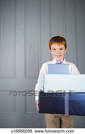 Stock Photo - boy with ginger hair holding presents. Fotosearch