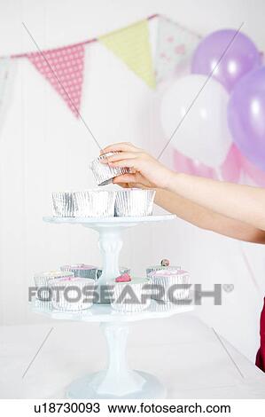 Stock Image - girl's hand taking cake from cake stand at birthday party. Fotosearch