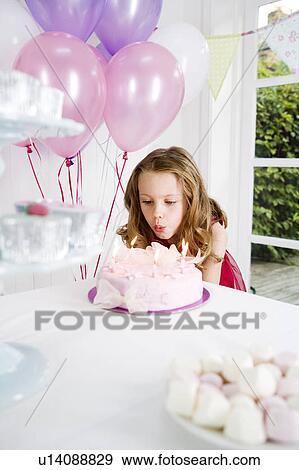Stock Photo - little girl blowing out candles on birthday cake. Fotosearch