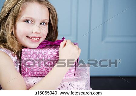 Stock Image - Young girl holding birthday presents. Fotosearch