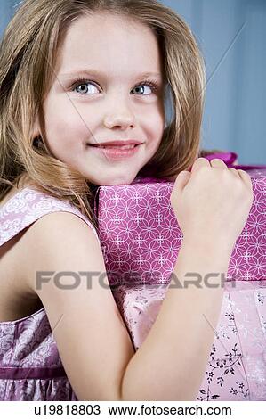 Stock Image - Young girl holding birthday presents. Fotosearch