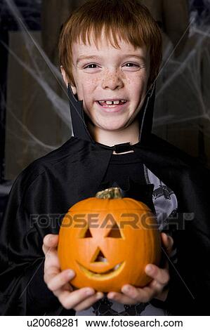 Boy in a skeleton costume at Hallowe'en, holding a pumpkin with a carved face View Large Photo Image Stock Image - Boy in a skeleton costume at Hallowe'en, holding a pumpkin with a carved face. Fotosearch