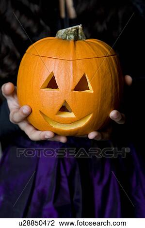 Child holding Hallowe'en pumpkin with a carved face View Large Photo Image Stock Image - Child holding Hallowe'en pumpkin with a carved face. Fotosearch
