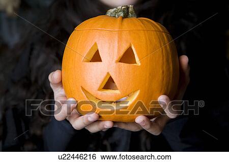 Child holding Hallowe'en pumpkin with a carved face View Large Photo Image Stock Photograph - Child holding Hallowe'en pumpkin with a carved face. Fotosearch