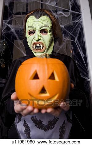 Child in a Count Dracula costume at Hallowe'en, holding a pumpkin with a carved face View Large Photo Image Stock Image - Child in a Count Dracula costume at Hallowe'en, holding a pumpkin with a carved face. Fotosearch