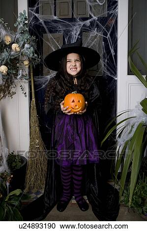 Girl in a witch's costume at a Hallowe'en party, holding a pumpkin View Large Photo Image Stock Image - Girl in a witch's costume at a Hallowe'en party, holding a pumpkin . Fotosearch