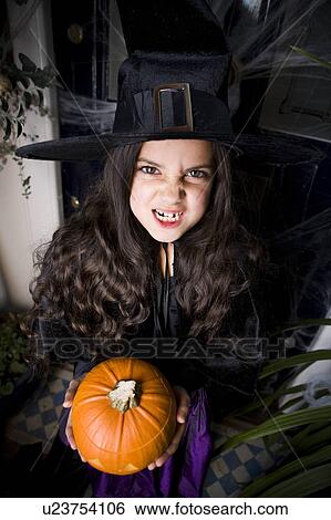 Girl in a witch's costume at a Hallowe'en party, holding a pumpkin View Large Photo Image Stock Photograph - Girl in a witch's costume at a Hallowe'en party, holding a pumpkin . Fotosearch