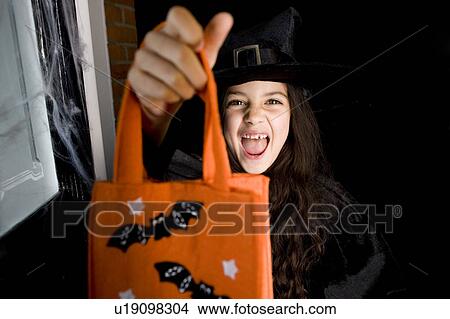 Girl in costume at a Hallowe'en party, holding an orange party bag View Large Photo Image Picture - Girl in costume at a Hallowe'en party, holding an orange party bag. Fotosearch