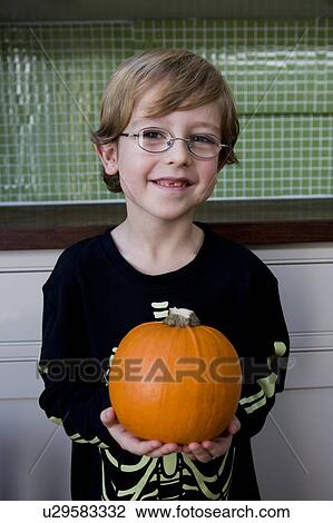 Stock Image - Little boy holding an orange Hallowe'en pumpkin. Fotosearch