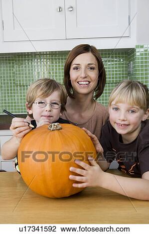Little girl and boy making a pumpkin lantern with their mother. View Large Photo Image Stock Image - Little girl and boy making a pumpkin lantern with their mother. . Fotosearch