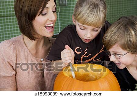 Little girl and boy making a pumpkin lantern with their mother. View Large Photo Image Stock Photo - Little girl and boy making a pumpkin lantern with their mother. . Fotosearch