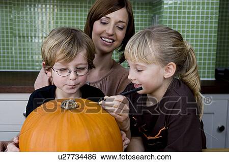 Little girl and boy making a pumpkin lantern with their mother. View Large Photo Image Stock Photograph - Little girl and boy making a pumpkin lantern with their mother. . Fotosearch