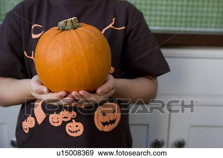Stock Photo - Little girl holding an orange Hallowe'en pumpkin. Fotosearch