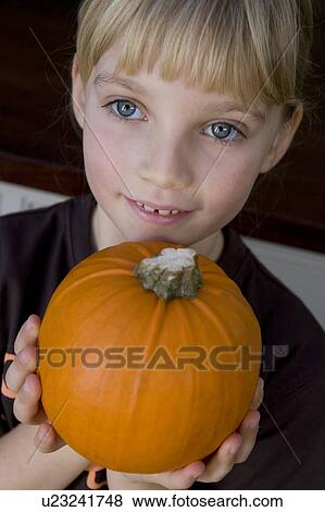 Little girl holding an orange Hallowe'en pumpkin View Large Photo Image Stock Photo - Little girl holding an orange Hallowe'en pumpkin. Fotosearch