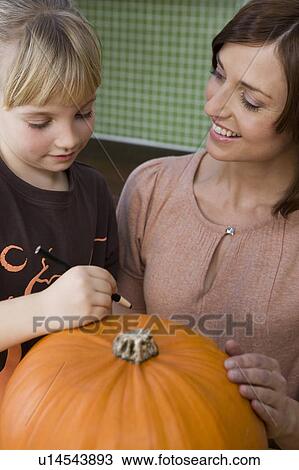 Mother and daughter carving a face in a Hallowe'en pumpkin View Large Photo Image Stock Image - Mother and daughter carving a face in a Hallowe'en pumpkin. Fotosearch