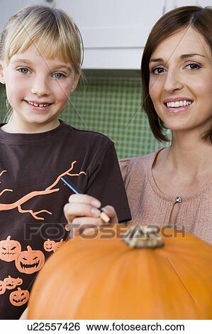 Mother and daughter carving a face in a Hallowe'en pumpkin View Large Photo Image Stock Photograph - Mother and daughter carving a face in a Hallowe'en pumpkin. Fotosearch