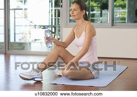 Stock Image - A woman sitting in a gym. Fotosearch