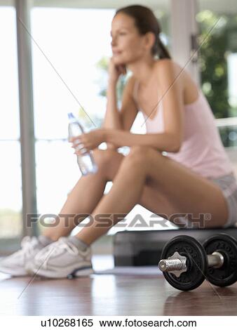 Stock Photography - A woman sitting in a gym. Fotosearch