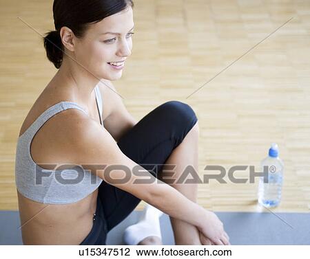 A young woman sitting on a yoga mat View Large Photo Image Stock Image - A young woman sitting on a yoga mat. Fotosearch