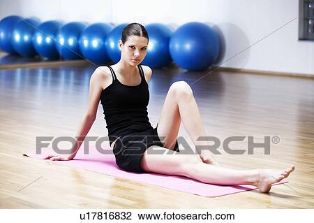 A young woman sitting on a yoga mat View Large Photo Image Stock Image - A young woman sitting on a yoga mat. Fotosearch