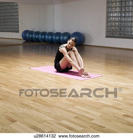 A young woman sitting on a yoga mat View Large Photo Image Stock Image - A young woman sitting on a yoga mat. Fotosearch