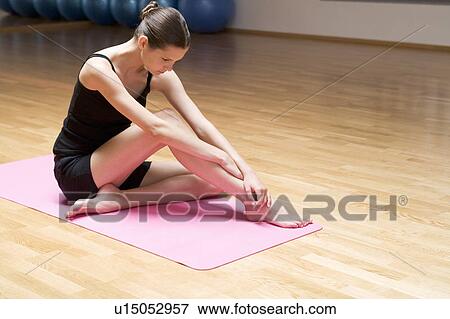 Stock Photo - A young woman sitting on a yoga mat. Fotosearch