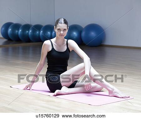 A young woman sitting on a yoga mat View Large Photo Image Stock Photo - A young woman sitting on a yoga mat. Fotosearch