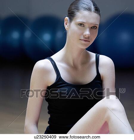 Stock Photo - A young woman sitting on a yoga mat. Fotosearch