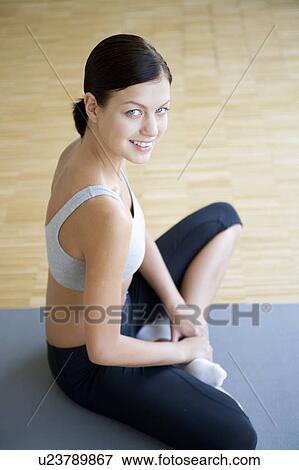A young woman sitting on a yoga mat View Large Photo Image Stock Photo - A young woman sitting on a yoga mat. Fotosearch