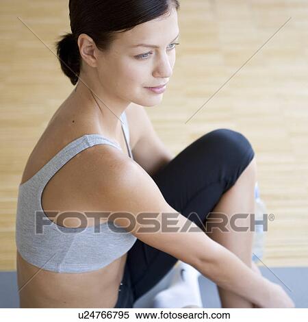 A young woman sitting on a yoga mat View Large Photo Image Stock Photography - A young woman sitting on a yoga mat. Fotosearch