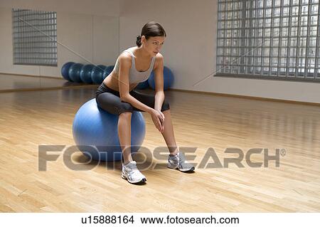 Picture - A young woman sitting on an exercise ball. Fotosearch