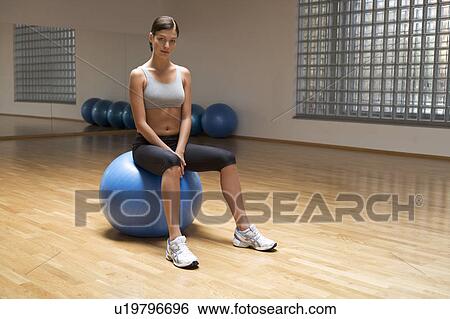 A young woman sitting on an exercise ball View Large Photo Image Stock Photograph - A young woman sitting on an exercise ball. Fotosearch