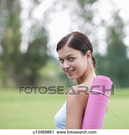 Stock Image - A young woman with a yoga mat. Fotosearch