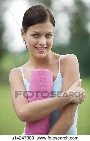 Stock Image - A young woman with a yoga mat. Fotosearch