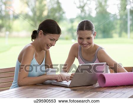 Stock Image - Two young with a laptop after a yoga class. Fotosearch